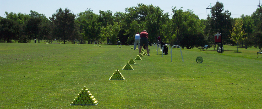 Golfers practicing on range. Pyramid of golf balls by each spot
